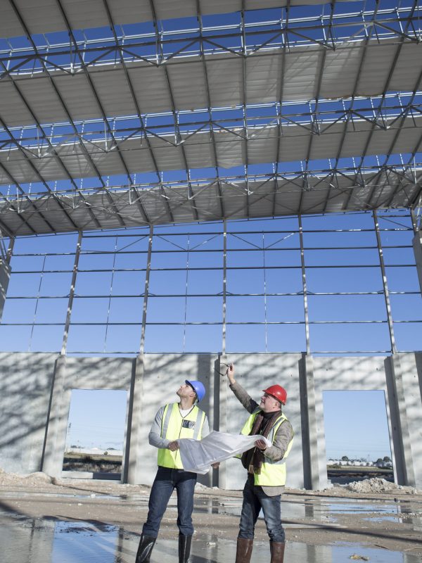 Surveyor and architect looking up at construction frame